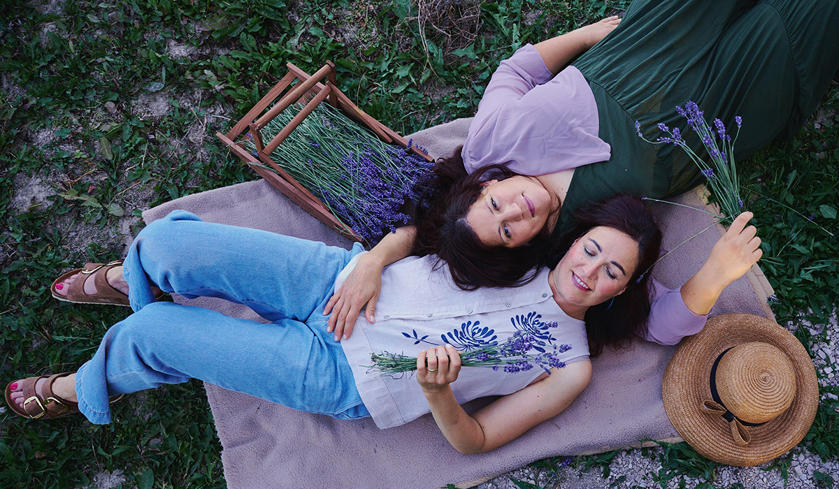 Martina und Kristina, Gründerinnen der KrisMar Naturkosmetikmanufaktur, liegend am Lavendelfeld